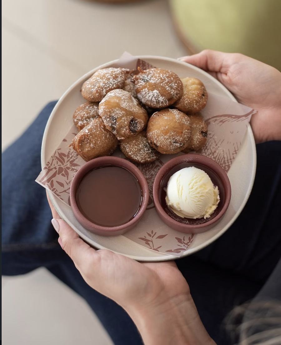 Buñuelos con azúcar glass, chocolate caliente y una bola de helado de vainilla